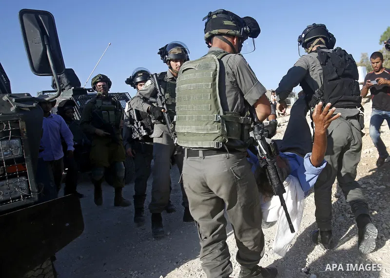 Israeli border policemen carry away a Palestinian man after Israeli troops demolished his shed near the West Bank village of Um AlKhair, south of Hebron August 9, 2016. Photo by Wisam Hashlamoun