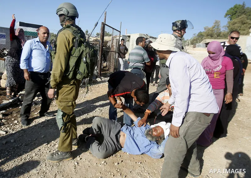 Israeli border policemen carry away a Palestinian man after Israeli troops demolished his shed near the West Bank village of Um AlKhair, south of Hebron August 9, 2016. Photo by Wisam Hashlamoun