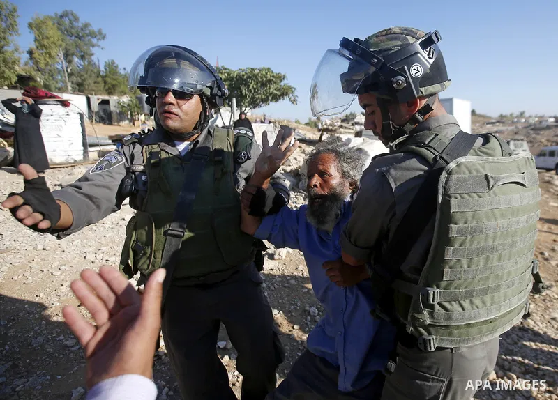 Israeli border policemen carry away a Palestinian man after Israeli troops demolished his shed near the West Bank village of Um AlKhair, south of Hebron August 9, 2016. Photo by Wisam Hashlamoun