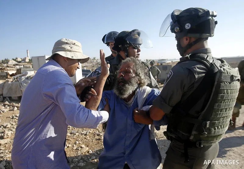 Israeli border policemen carry away a Palestinian man after Israeli troops demolished his shed near the West Bank village of Um AlKhair, south of Hebron August 9, 2016. Photo by Wisam Hashlamoun