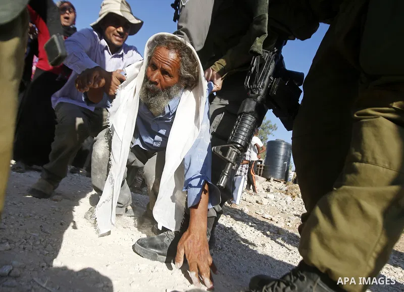 Israeli border policemen carry away a Palestinian man after Israeli troops demolished his shed near the West Bank village of Um AlKhair, south of Hebron August 9, 2016. Photo by Wisam Hashlamoun
