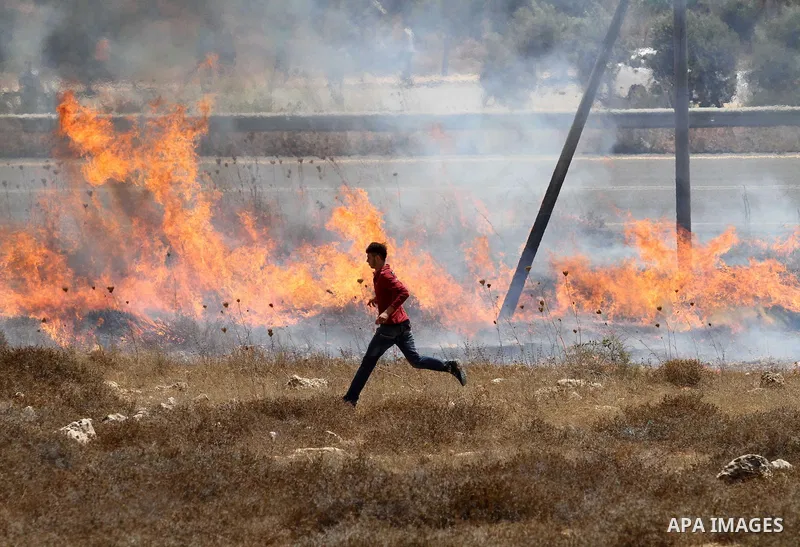 A Palestinian protester runs for cover from a tear gas canister fired by Israeli soldiers during clashes in the village of Qusra on August 9, 2016 in the occupied West Bank. Qusra is just a few kilometres (miles) north o...
