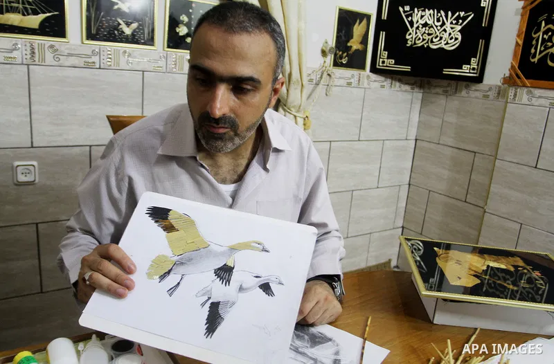 A Palestinian artist, Hossam Abed, fills the paintings from straw "wheat stalks", at his house, in Rafah in the southern Gaza strip, on August 10, 2016. Photo by Abed Rahim Khatib