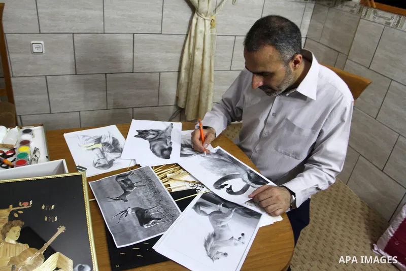 A Palestinian artist, Hossam Abed, fills the paintings from straw "wheat stalks", at his house, in Rafah in the southern Gaza strip, on August 10, 2016. Photo by Abed Rahim Khatib