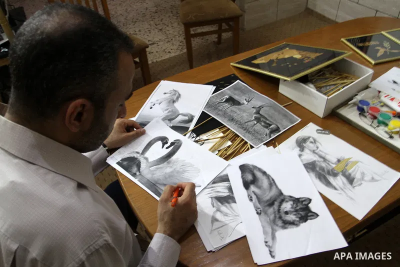 A Palestinian artist, Hossam Abed, fills the paintings from straw "wheat stalks", at his house, in Rafah in the southern Gaza strip, on August 10, 2016. Photo by Abed Rahim Khatib