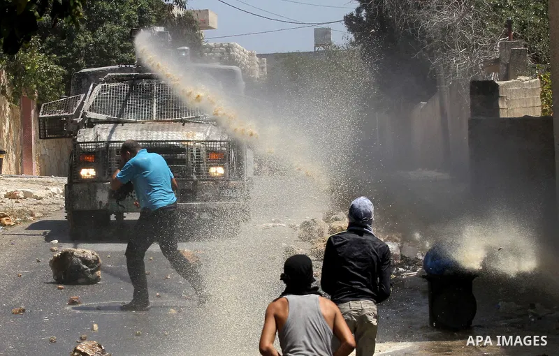 Palestinian protesters hurl stones towards an Israeli security forces vehicle spraying a foul-smelling water known as "skunk" during clashes following a weekly demonstration against the expropriation of Palestinian land...