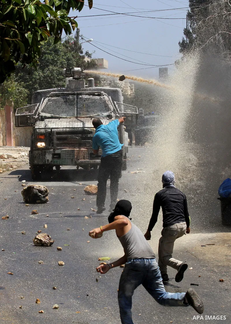Palestinian protesters hurl stones towards an Israeli security forces vehicle spraying a foul-smelling water known as "skunk" during clashes following a weekly demonstration against the expropriation of Palestinian land...