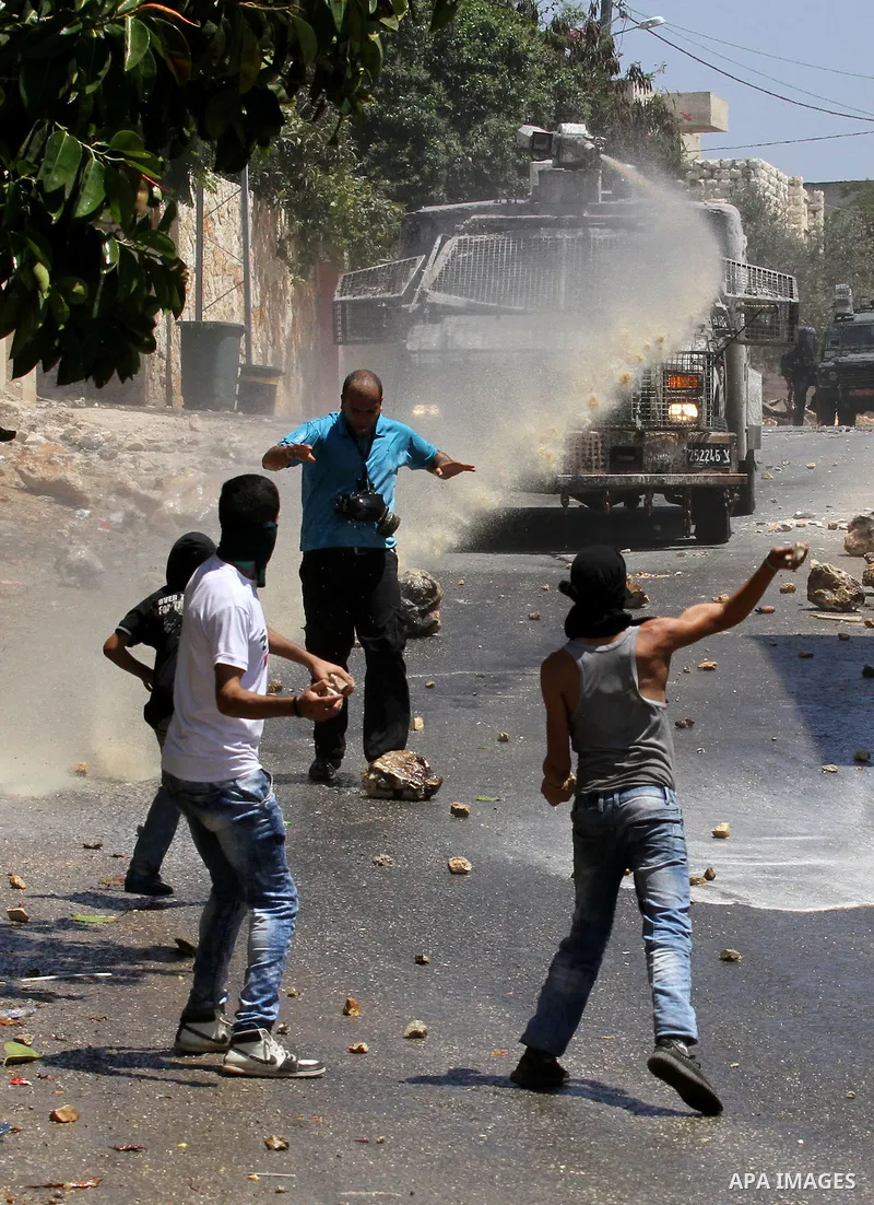 Palestinian protesters hurl stones towards an Israeli security forces vehicle spraying a foul-smelling water known as "skunk" during clashes following a weekly demonstration against the expropriation of Palestinian land...