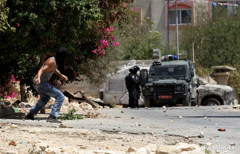 A Palestinian protester hurls stones towards Israeli security forces during clashes following a weekly demonstration against the expropriation of Palestinian land by Israel on August 12, 2016, in the village of Kfar Qadd...