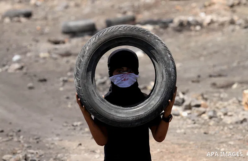 A Palestinian protester carries tires during clashes with Israeli security forces following a weekly demonstration against the expropriation of Palestinian land by Israel on August 12, 2016, in the village of Kfar Qaddum...