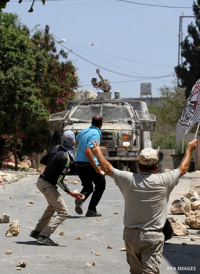 Palestinian protesters hurl stones towards an Israeli security forces vehicle spraying a foul-smelling water known as "skunk" during clashes following a weekly demonstration against the expropriation of Palestinian land...