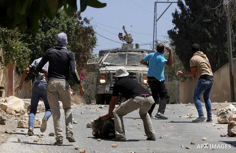 Palestinian protesters hurl stones towards an Israeli security forces vehicle spraying a foul-smelling water known as "skunk" during clashes following a weekly demonstration against the expropriation of Palestinian land...