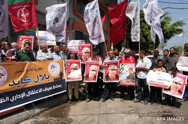 Palestinians hold posters against administrative detention and in support of Palestinian prisoner Bilal Kayed (portrait), who has been fasting for almost two months over his detention without trial, in Gaza city, on Augu...