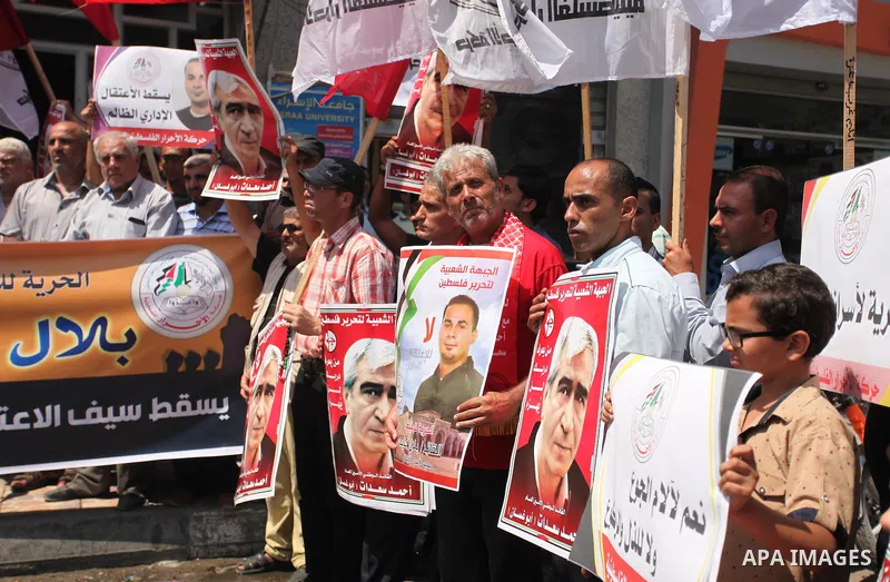 Palestinians hold posters against administrative detention and in support of Palestinian prisoner Bilal Kayed (portrait), who has been fasting for almost two months over his detention without trial, in Gaza city, on Augu...