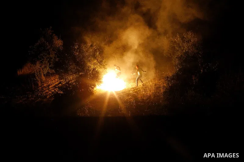 Palestinians put out a fire caused by flares shot by Israeli soldiers as Israeli troops set explosives to partially blow up the family house of Palestinian assailant Mohammad Tarayra in the West Bank village of Bani Naem...