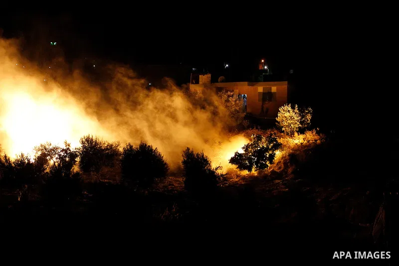 Palestinians put out a fire caused by flares shot by Israeli soldiers as Israeli troops set explosives to partially blow up the family house of Palestinian assailant Mohammad Tarayra in the West Bank village of Bani Naem...
