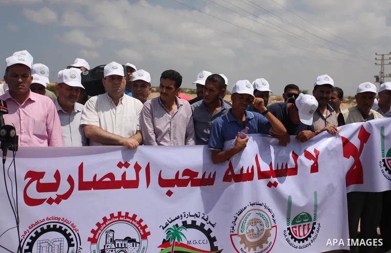Palestinian traders hold banners during a protest against the Israeli authorities to withdraw permits for some of the traders and to prevent their entry into the West Bank, in front of the Erez crossing point with Israel...