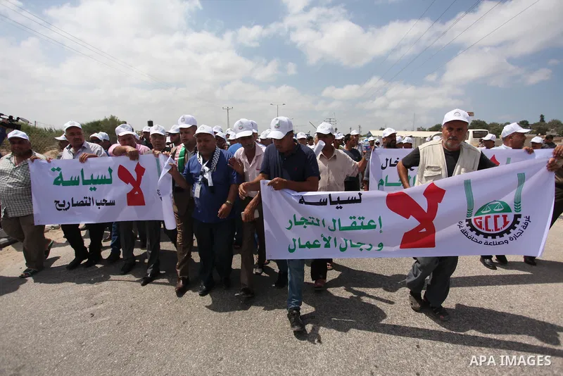Palestinian traders hold banners during a protest against the Israeli authorities to withdraw permits for some of the traders and to prevent their entry into the West Bank, in front of the Erez crossing point with Israel...