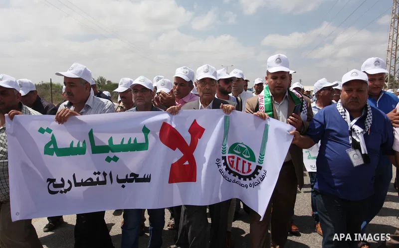 Palestinian traders hold banners during a protest against the Israeli authorities to withdraw permits for some of the traders and to prevent their entry into the West Bank, in front of the Erez crossing point with Israel...