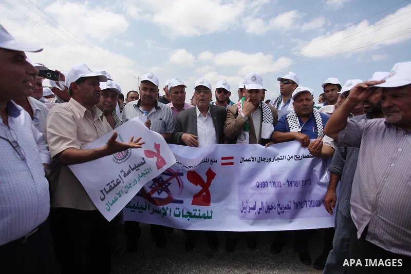Palestinian traders hold banners during a protest against the Israeli authorities to withdraw permits for some of the traders and to prevent their entry into the West Bank, in front of the Erez crossing point with Israel...