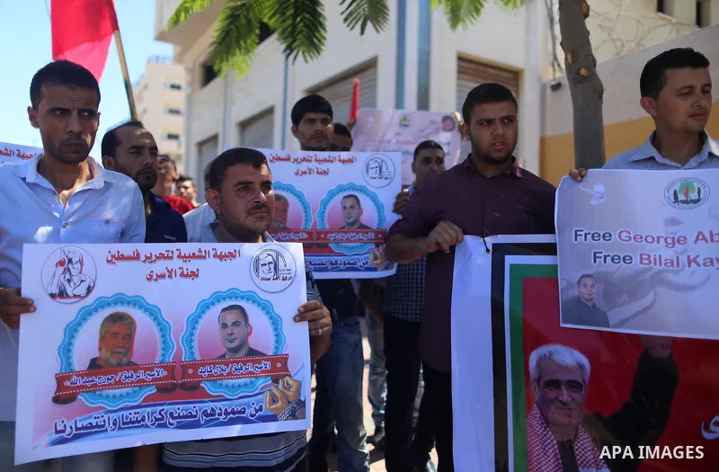 Palestinians hold posters against administrative detention and in support of Palestinian prisoner Bilal Kayed (portrait), who has been fasting for almost two months over his detention without trial, in Gaza city, on Augu...
