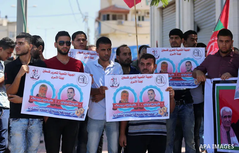Palestinians hold posters against administrative detention and in support of Palestinian prisoner Bilal Kayed (portrait), who has been fasting for almost two months over his detention without trial, in Gaza city, on Augu...