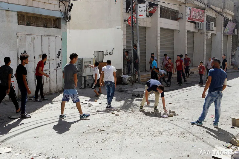 Palestinian youths throw stones towards Israeli soldiers as they conduct searches in the Palestinian al-Fawwar refugee camp, south of the West Bank city of Hebron, on August 16, 2016. Twenty-five Palestinians were wounde...