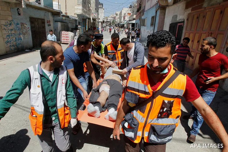 Members of the Palestinian Red Crescent and medics evacuate on a stretcher a Palestinian youth who was wounded during clashes with Israeli soldiers conducting searches in the Palestinian al-Fawwar refugee camp, south of...