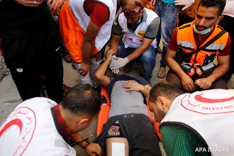 Members of the Palestinian Red Crescent and medics evacuate on a stretcher a Palestinian youth who was wounded during clashes with Israeli soldiers conducting searches in the Palestinian al-Fawwar refugee camp, south of...