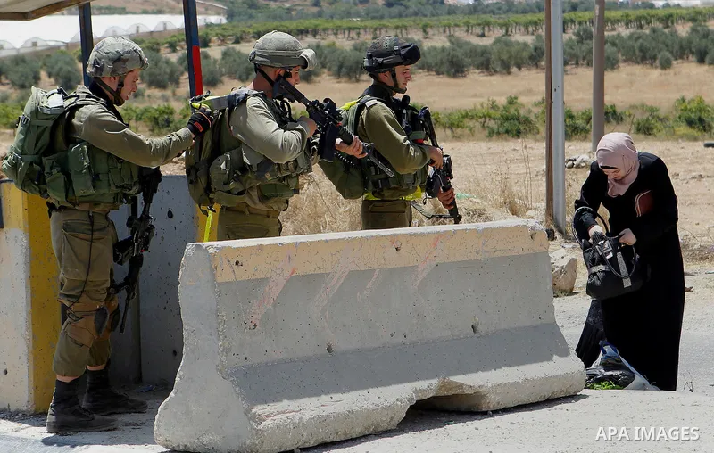 Israeli soldiers search a Palestinian woman at the main entrance of the Palestinian al-Fawwar refugee camp, south of the West Bank city of Hebron, on August 16, 2016 as the Israeli army conducts searches. Twenty-five Pal...