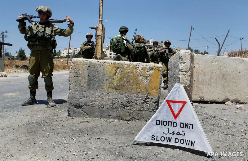 Israeli soldiers stand guard at the main entrance of the Palestinian al-Fawwar refugee camp, south of the West Bank city of Hebron, on August 16, 2016 as the Israeli army conducts searches. Twenty-five Palestinians were...