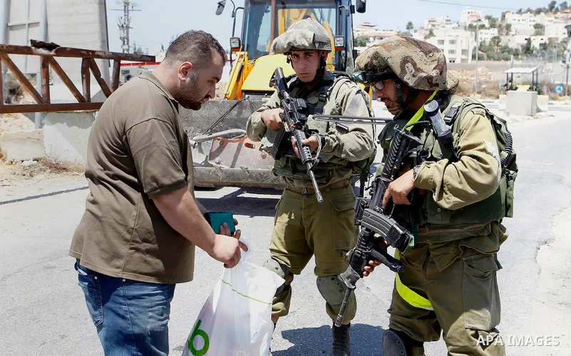 Israeli soldiers search a Palestinian man at the main entrance of the Palestinian al-Fawwar refugee camp, south of the West Bank city of Hebron, on August 16, 2016 as the Israeli army conducts searches. Twenty-five Pales...