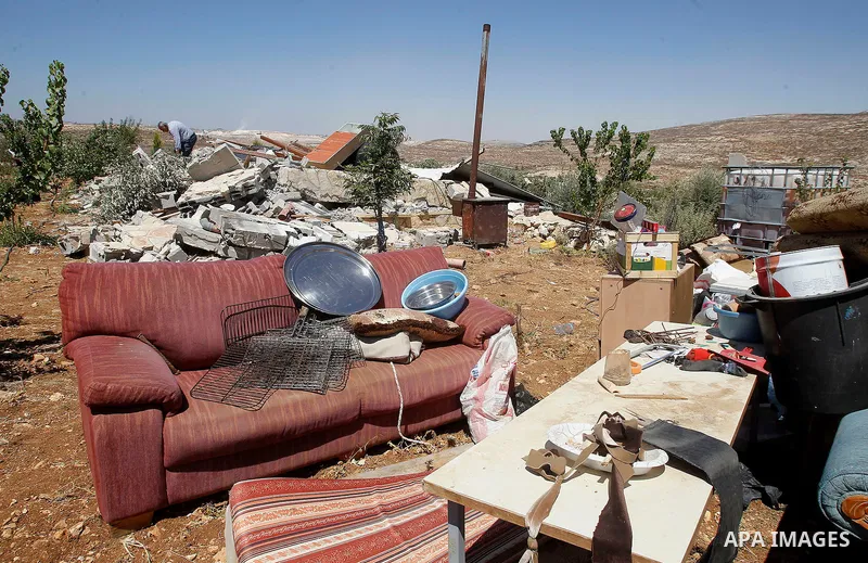 A Palestinian man searches for his belongings after Israeli troops demolished his house in the West Bank village of Saeer, near Hebron August 16, 2016. Photo by Wisam Hashlamoun