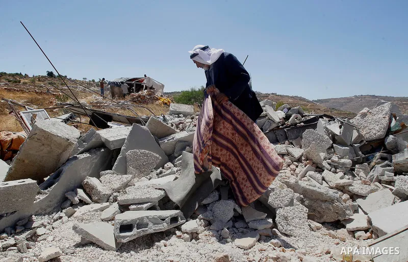 A Palestinian man searches for his belongings after Israeli troops demolished his house in the West Bank village of Saeer, near Hebron August 16, 2016. Photo by Wisam Hashlamoun