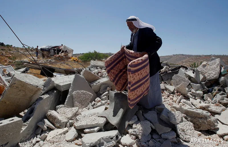 A Palestinian man searches for his belongings after Israeli troops demolished his house in the West Bank village of Saeer, near Hebron August 16, 2016. Photo by Wisam Hashlamoun