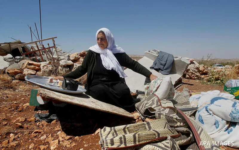 A Palestinian woman searches for her belongings after Israeli troops demolished her house in the West Bank village of Saeer, near Hebron August 16, 2016. Photo by Wisam Hashlamoun