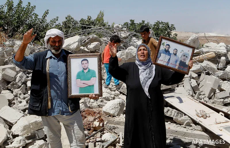 A Palestinian woman gestures as she holds a picture of her sons, two of whom are held in Israeli jails, after Israeli troops demolished her house in the West Bank village of Saeer, near Hebron August 16, 2016. Photo by W...