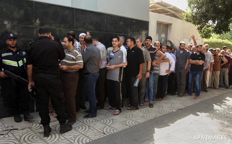 Employees of former Palestinian government in Gaza Strip wait to receive their salaries at a Post Office in Gaza city on August 17, 2016. The Emir of Qatar, Sheikh Tamim bin Hamad al-Thani, has ordered paying a total of...