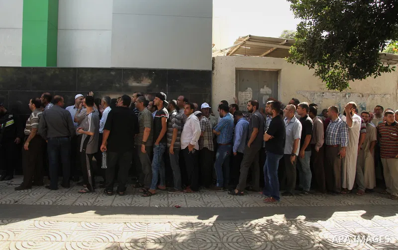 Employees of former Palestinian government in Gaza Strip wait to receive their salaries at a Post Office in Gaza city on August 17, 2016. The Emir of Qatar, Sheikh Tamim bin Hamad al-Thani, has ordered paying a total of...