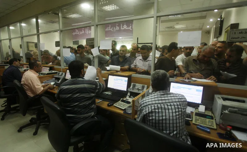 Employees of former Palestinian government in Gaza Strip wait to receive their salaries at a Post Office in Gaza city on August 17, 2016. The Emir of Qatar, Sheikh Tamim bin Hamad al-Thani, has ordered paying a total of...