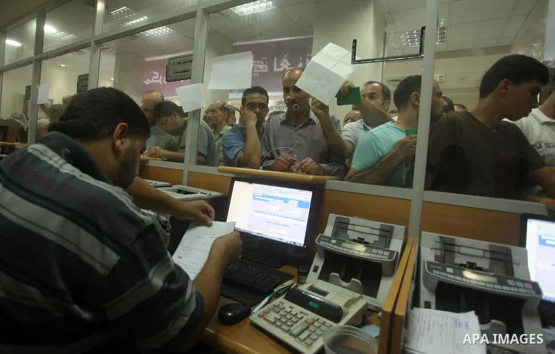 Employees of former Palestinian government in Gaza Strip wait to receive their salaries at a Post Office in Gaza city on August 17, 2016. The Emir of Qatar, Sheikh Tamim bin Hamad al-Thani, has ordered paying a total of...
