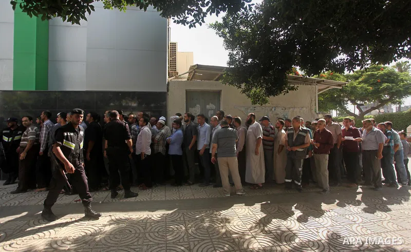 Employees of former Palestinian government in Gaza Strip wait to receive their salaries at a Post Office in Gaza city on August 17, 2016. The Emir of Qatar, Sheikh Tamim bin Hamad al-Thani, has ordered paying a total of...