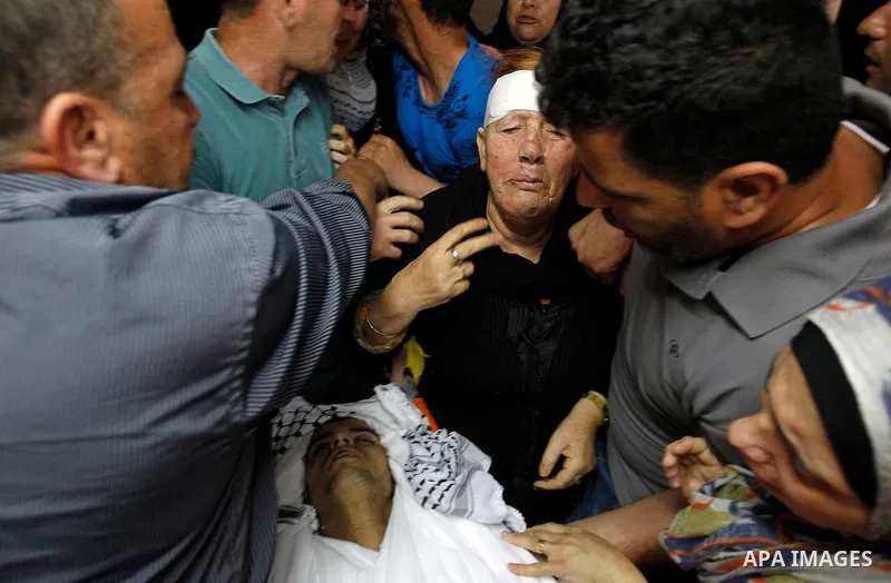 Relatives mourn next to the body of Palestinian Mohammed Abu Hashash, who was shot dead the day before during clashes with Israeli forces, before his funeral on August 17, 2016 in the al-Fawwar Palestinian refugee camp,...