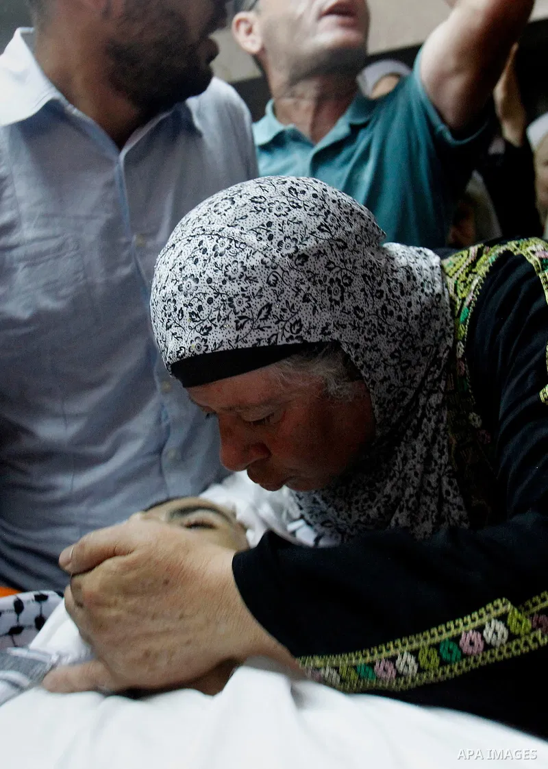 Relatives mourn next to the body of Palestinian Mohammed Abu Hashash, who was shot dead the day before during clashes with Israeli forces, before his funeral on August 17, 2016 in the al-Fawwar Palestinian refugee camp,...