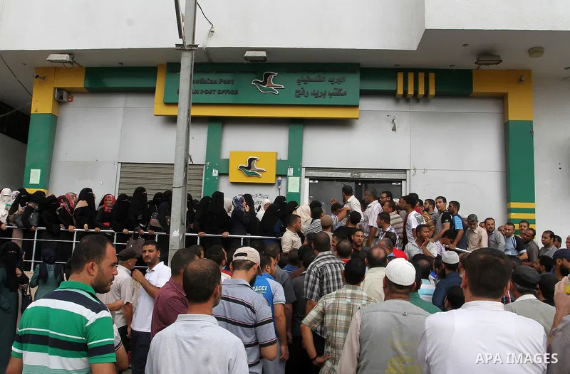 Employees of former Palestinian government in Gaza Strip wait to receive their salaries at a Post Office in Rafah in the southern Gaza strip on August 17, 2016. The Emir of Qatar, Sheikh Tamim bin Hamad al-Thani, has ord...