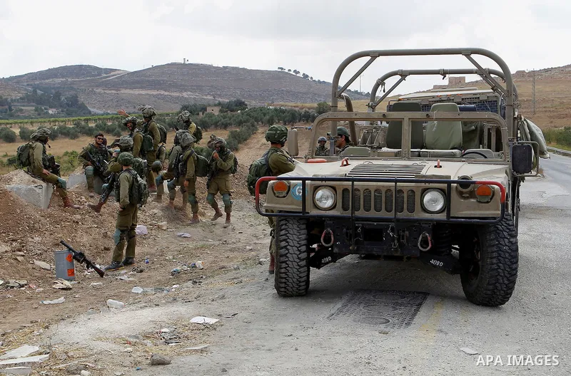 Israeli soldiers stand guard at the main entrance of the Palestinian al-Fawwar refugee camp, south of the West Bank city of Hebron, on August 17, 2016. Photo by Wisam Hashlamoun