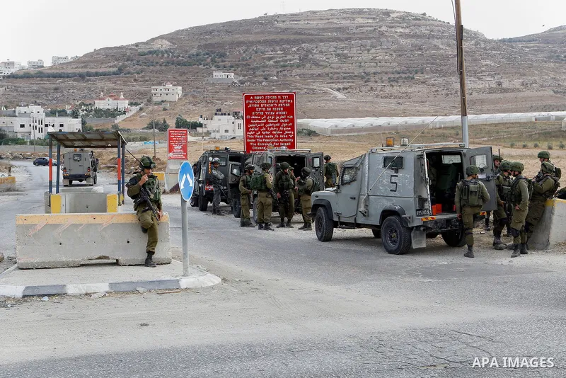 Israeli soldiers stand guard at the main entrance of the Palestinian al-Fawwar refugee camp, south of the West Bank city of Hebron, on August 17, 2016. Photo by Wisam Hashlamoun