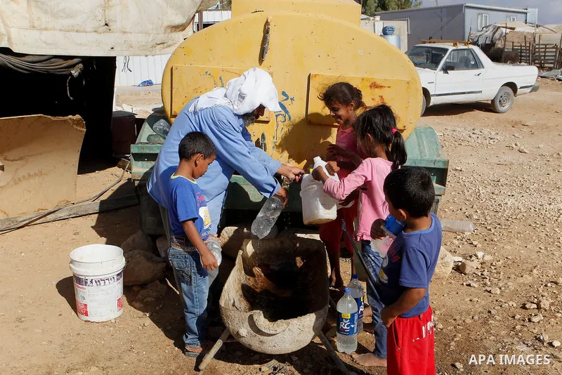 Palestinians fill plastic bottles and jerry cans with drinking water from a water tank in the West Bank village of Um Alkhair south of Hebron on August 17, 2016. Photo by Wisam Hashlamoun
