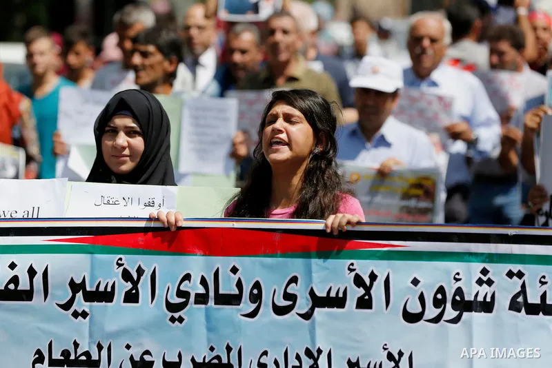 Palestinians hold posters against administrative detention and in support of Palestinian prisoner Bilal Kayed (portrait), who has been fasting for almost two months over his detention without trial, in the West Bank city...