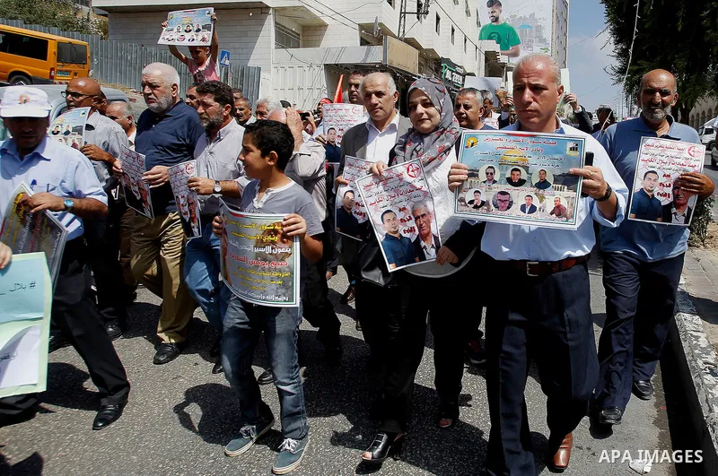 Palestinians hold posters against administrative detention and in support of Palestinian prisoner Bilal Kayed (portrait), who has been fasting for almost two months over his detention without trial, in the West Bank city...
